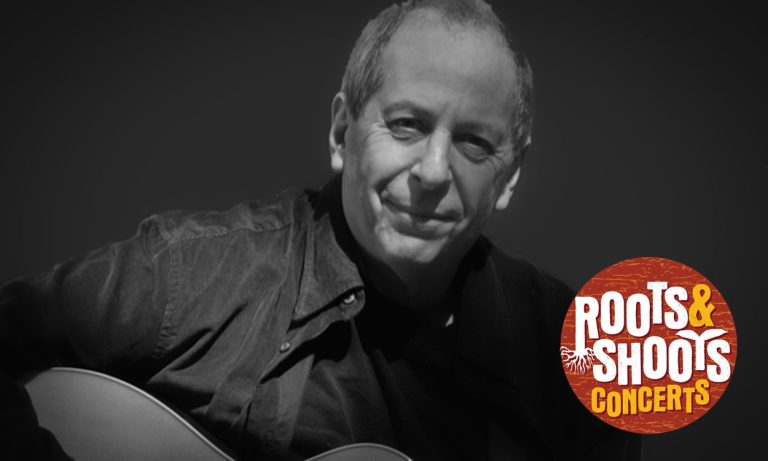 Black and white photo of Steve Katz playing the guitar with a Roots & Shoots logo overlaid